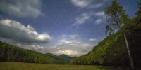 Cataloochee Valley is lit up by a near full moon as the clouds and stars fill the nighttime sky in the Great Smoky Mountains National Park, North Carolina.